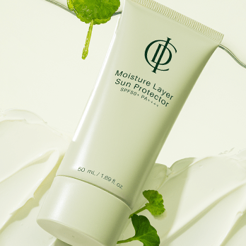 Tube of 'Moisture Layer Sun Protector' with green leaves on a light background