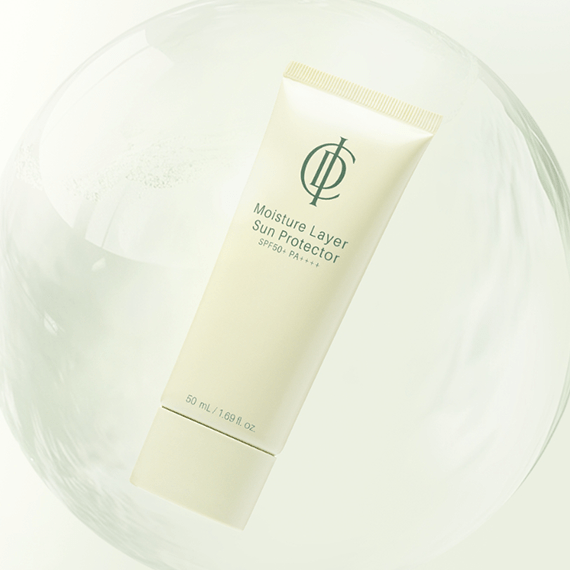 A tube of Moisture Layer Sun Protector SPF 50+ by Chantilly Organics, featuring a cream-colored tube with green text and logo, resting inside a clear glass sphere on a white background.